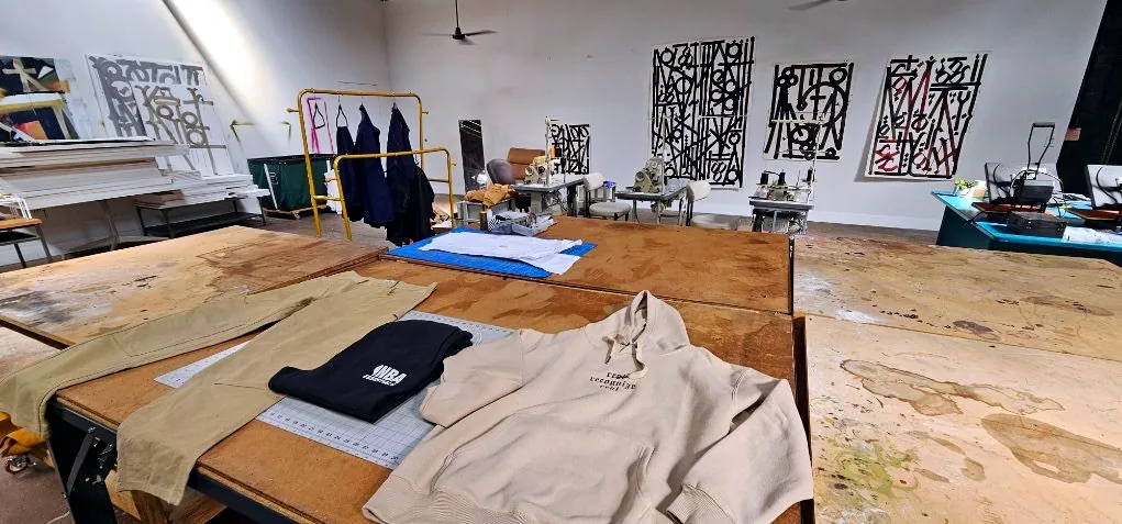 Cutting tables with garments laid out and art on the wall
