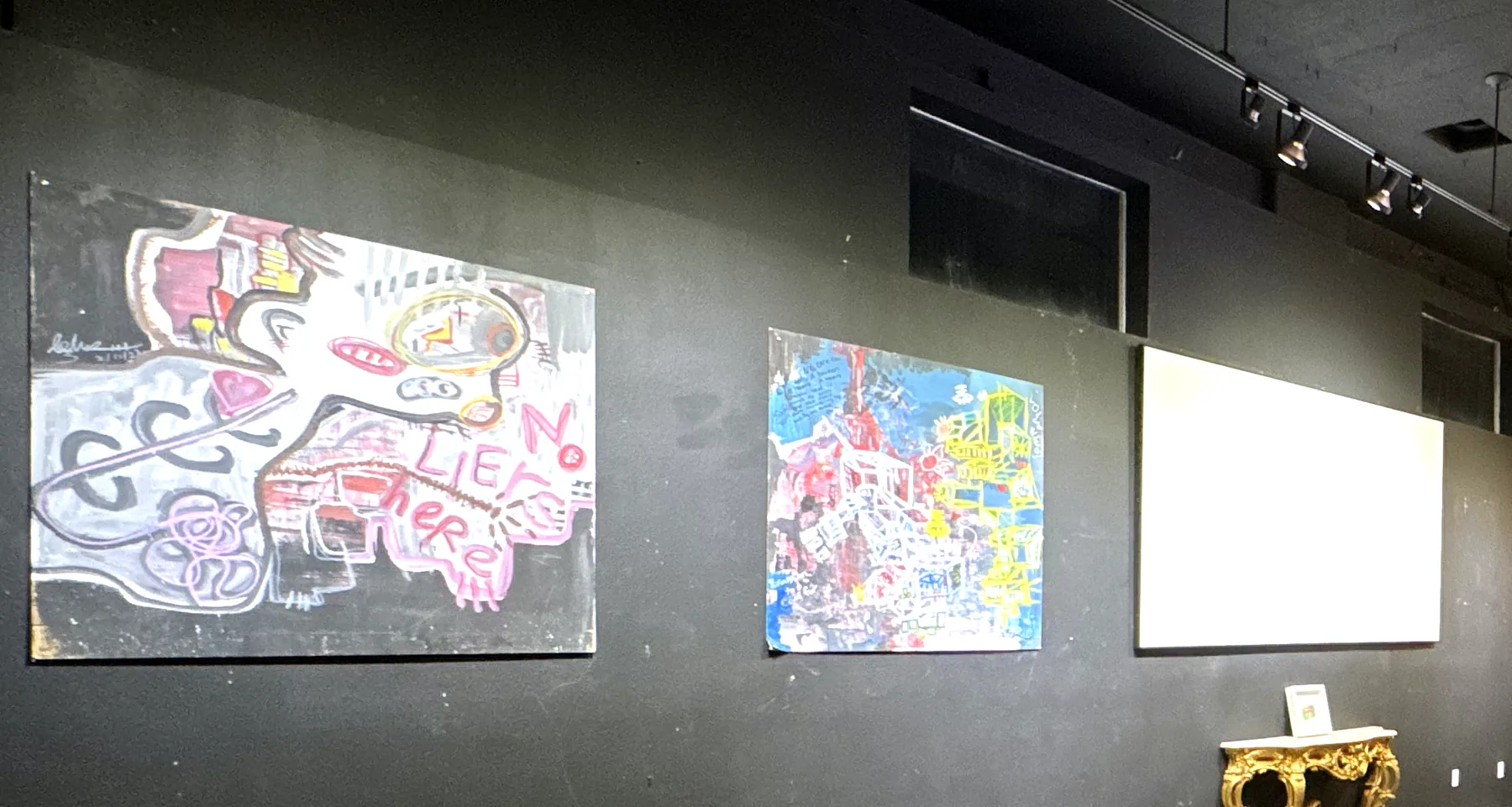 Gallery wall with large paintings and track lighting