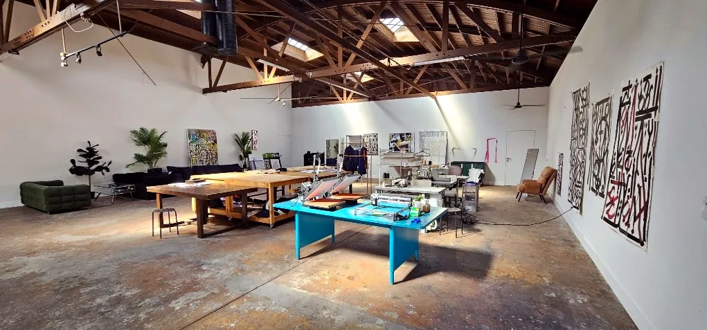 Open loft with wood beam ceiling, long tables and art on the walls